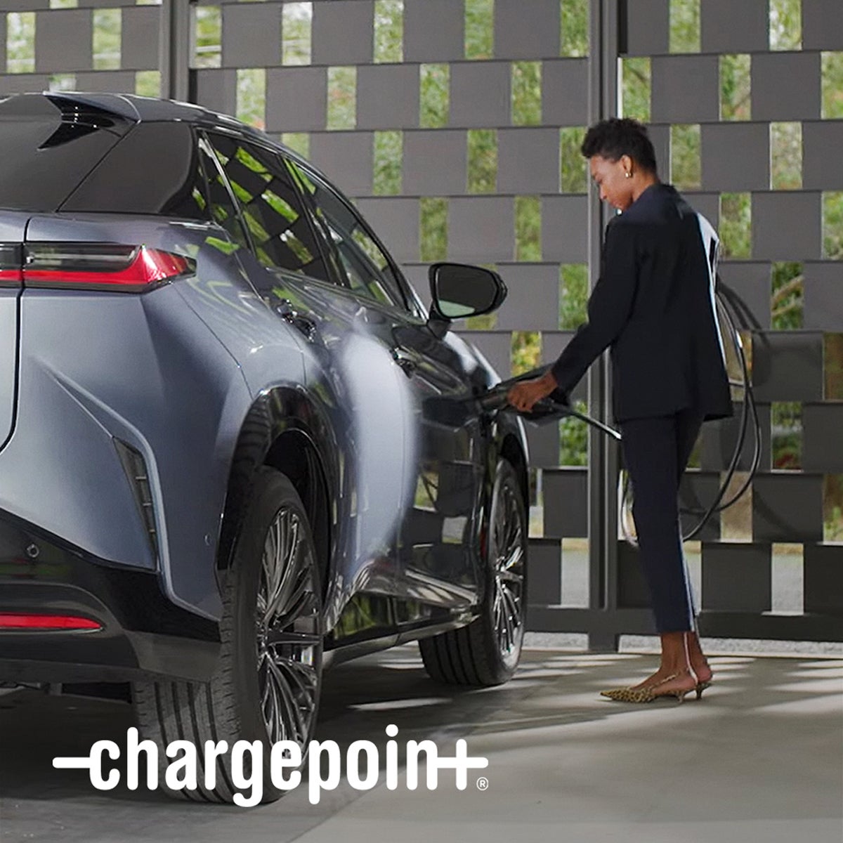 A person plugs a charger into their vehicle's charging port.